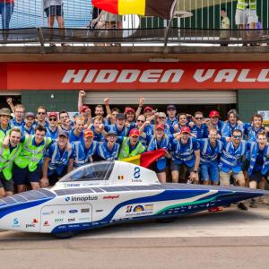 Team Innoptus stood behind a solar car 