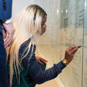 A person knelt down writing on a white board