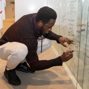 A person knelt down writing on a white board