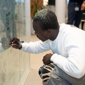 A person knelt down writing on a white board