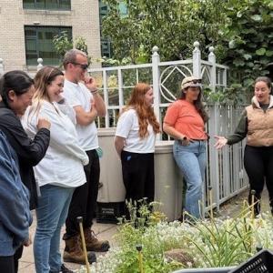DP World volunteers gathered on the YWCA Rooftop Garden as an instructor explains the day’s tasks, surrounded by raised beds and greenery.