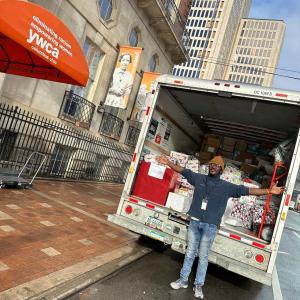Bath & Body Works associate stands in front of a special delivery of Bath & Body Works personal care and home fragrance product donation to the YWCA’s Women’s Residency Program.
