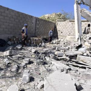 Workers stand among the rubble of the Huqah health facility 