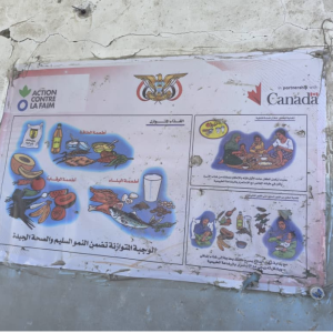 A faded Action Against Hunger poster of nutritional information hangs on one of the remaining walls