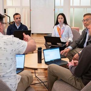 Zhang and his team seated around a table with laptops out