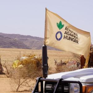 Action Against Hunger flag waves in front of vehicle.