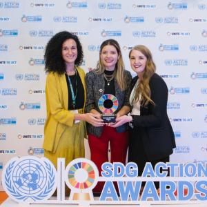 Three smiling people holding an award.