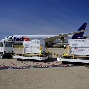 Crates arriving on tarmac next to FedEx airplane