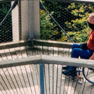 a person pushing another in a wheelchair across a bridge