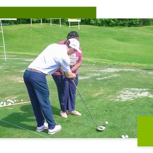 An instructor helping another with a golf club.