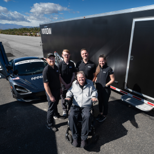 People collected together in front of a car