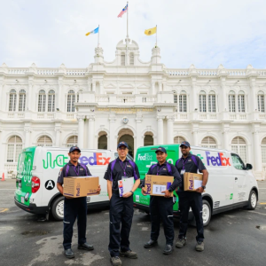FedEx employees holding packages, next to vehicles