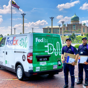 FedEx employees holding packages, next to vehicles