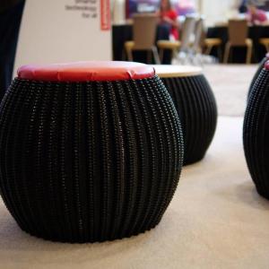 Multiple black stools made by the 3D printer on display.