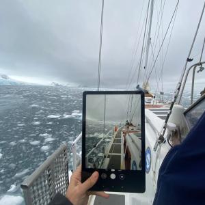 tablet viewing the bow of a small ship in icy water