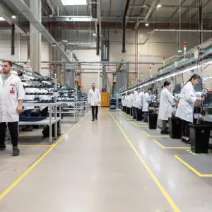 Long view at a manufacturing plant. People working on both sides of an aisle.