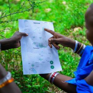 two people holding a piece of paper with one pointing to something