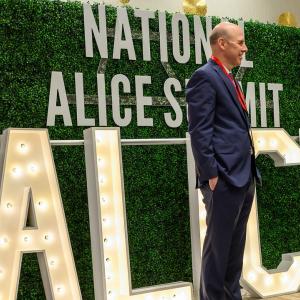 Two people talking in front of "National ALICE Summit" sign.