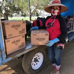 A worker holding a box with "always" logo, other boxes on an open cart next to them