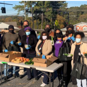 A row of people behind a table of produce.