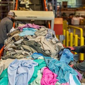 A person next to a line of waste textiles.