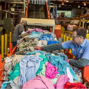 A person sorting through a line of waste apparel
