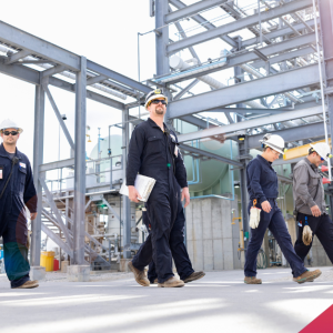 Workers in hardhats walking outside at a plant