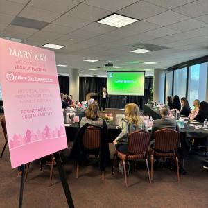 People seated in a conference room a sign "Mary Kay welcomes our legacy partner Arbor Day Foundation."