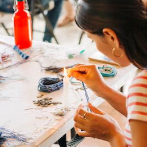 An artisan crafting a bracelet at a table