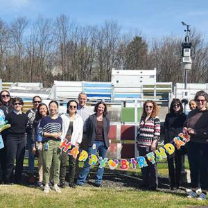 A group posed outside holding a banner "Happy Birthday".