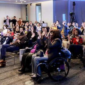 A group of seated people waving both hands.