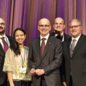 A group posed, one holding an award.