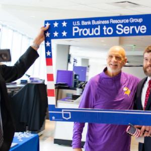 Employee holding up a selfie frame and taking a photo of two people in the frame