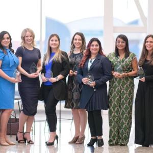 A group of people in a row, each holding an award.