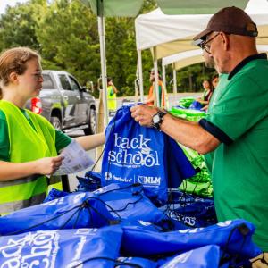 Volunteers organizing backpacks of school supplies