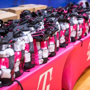 Multiple t-mobile rucksacks stacked on top of tables 