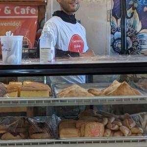 An employee behind a display case filled with bakery items.