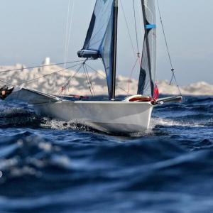 Two people leaning far out of a sailboat on open water.