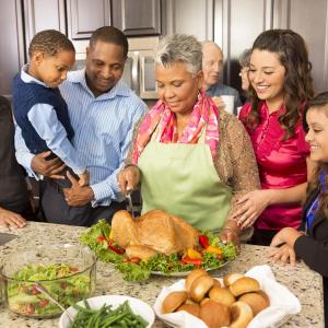 A smiling family collected around a Thanksgiving turkey being carved