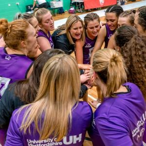 basketball team huddles with hands in the center