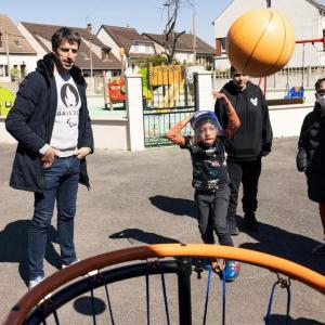A child throwing a basketball as adults watch.