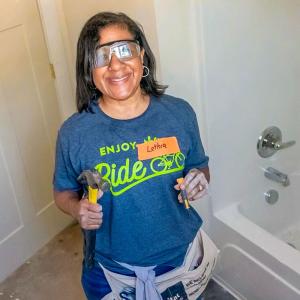 A smiling volunteers holding a hammer.