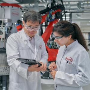 Two people wearing safety goggles and wearing white coats