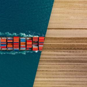 Image split in two parts, half a shipping container in the ocean and half a tractor tilling a field. 