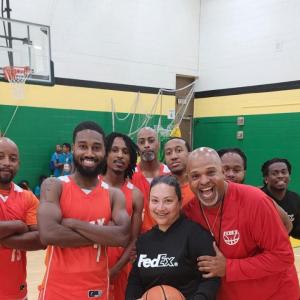 A group of adults and a child holding a basketball in a gymnasium.