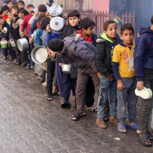 Palestinian children carry pots as they queue to receive food cooked by a charity kitchen, amid shortages in food supplies, as the conflict between Israel and Hamas continues, in Rafah in the southern Gaza Strip December 14, 2023./ Photo by Saleh Salem for Reuters. 