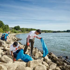 People collecting trash on a rocky beach.