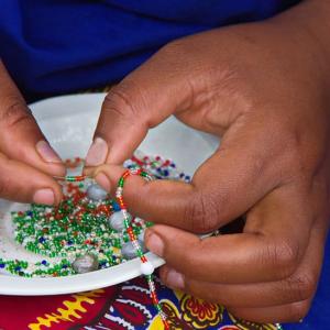 Close up of a person stringing beads.