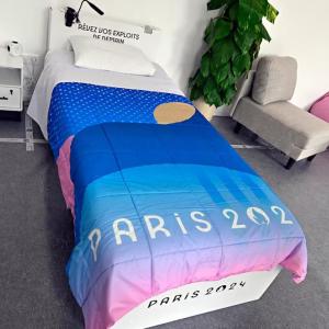 A bedroom scene with a "Paris 2024" comforter on the bed.