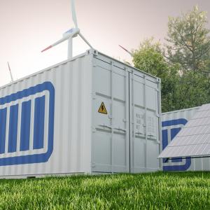 A storage container with a battery symbol on the side, outside next to solar panels and wind turbines.